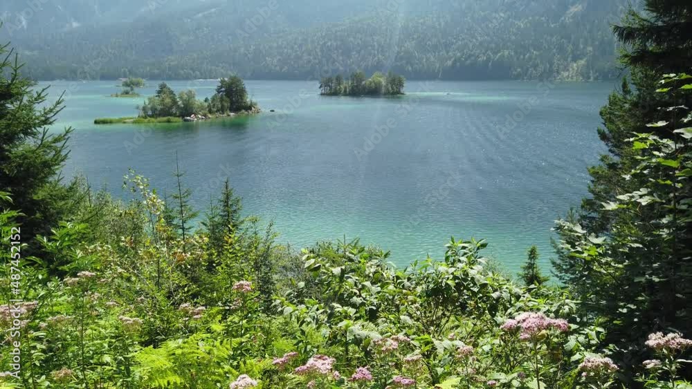 Entspannende, ruhige Wellen, kristallklar smaragdgrünes Wasser, von unten nach oben Ansicht. Immergrünen Wald, spektakuläres Inseln Panorama. Wandern - Bayern Alps, Eibsee, Zugspitze, Deutschland.