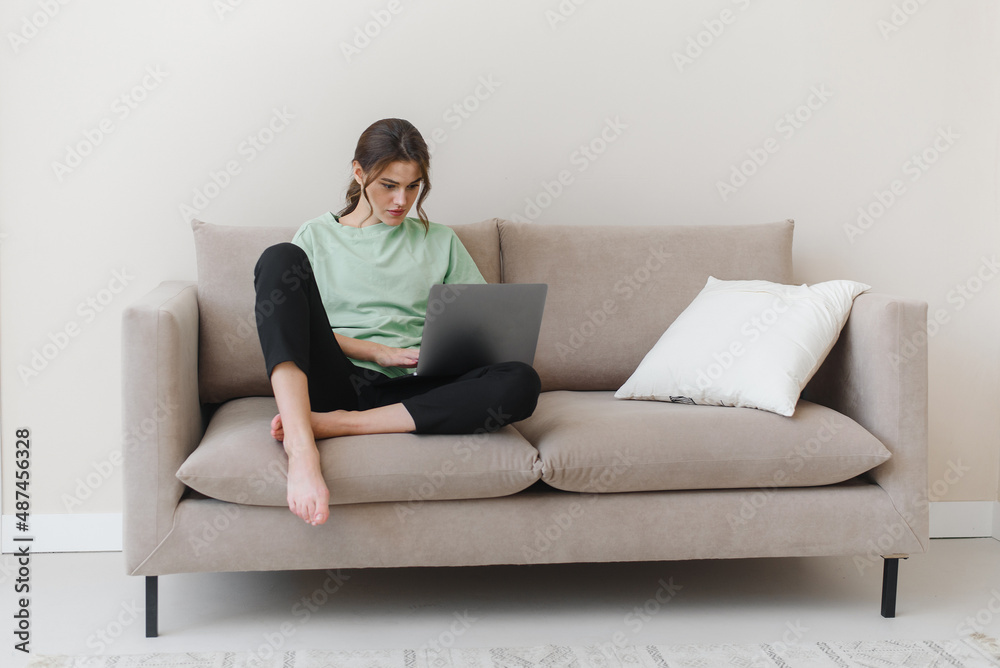 Focused young woman working from home or doing online shopping in living room. Focused young woman working from home or doing online shopping in living room.