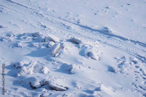 Ski track. Animal tracks in the snow. Winter background. The surface of the river after a snowfall with fragments of ice floes.