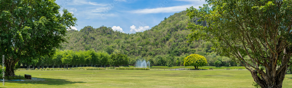 Panorama photo of beautiful lawn and mountains in the background and there was a fountain in the middle of the lawn beautiful natural view