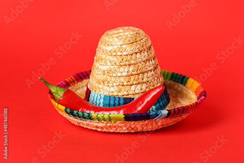 Mexican sombrero and hot chili pepper on red background