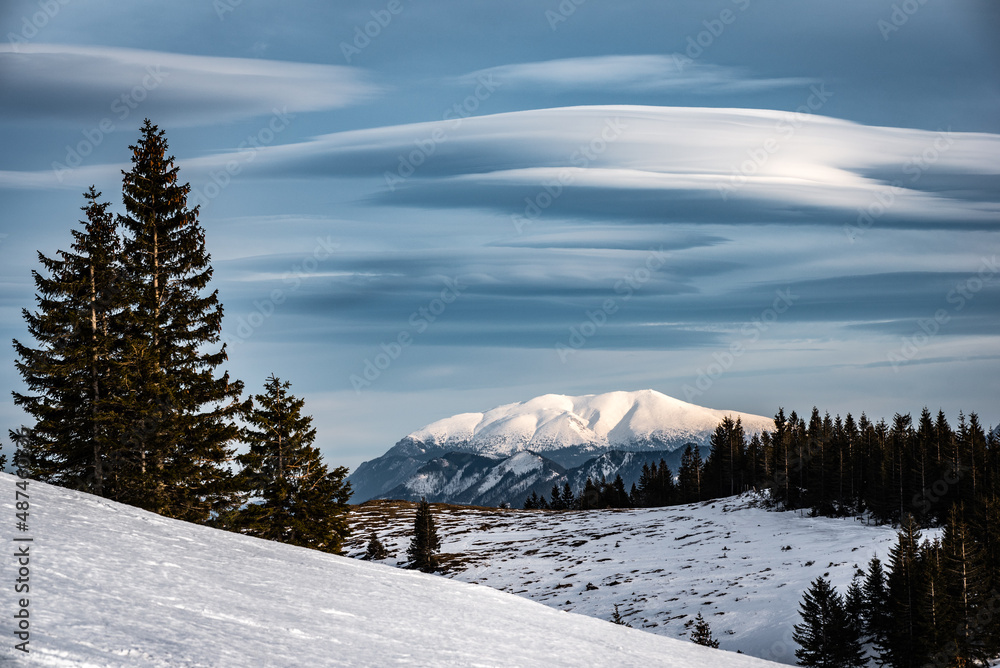 Obraz premium Winterlandschaft mit schneebedecktem Berg und interessanter Wolkenformation