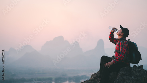 Success man hiker drink water at cliff edge on mountain top.Concept of adventure travel