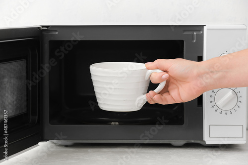 Woman taking cup with milk ...