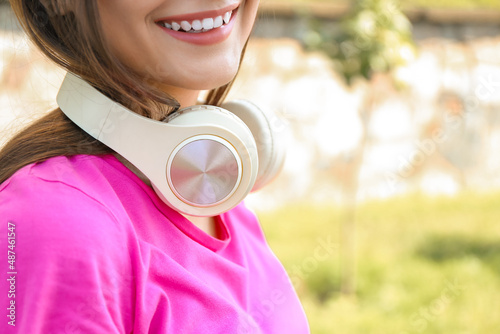 Pretty young woman with headphones outdoors, closeup