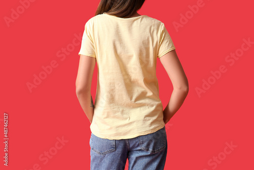 Young woman in blank t-shirt on color background, back view photo