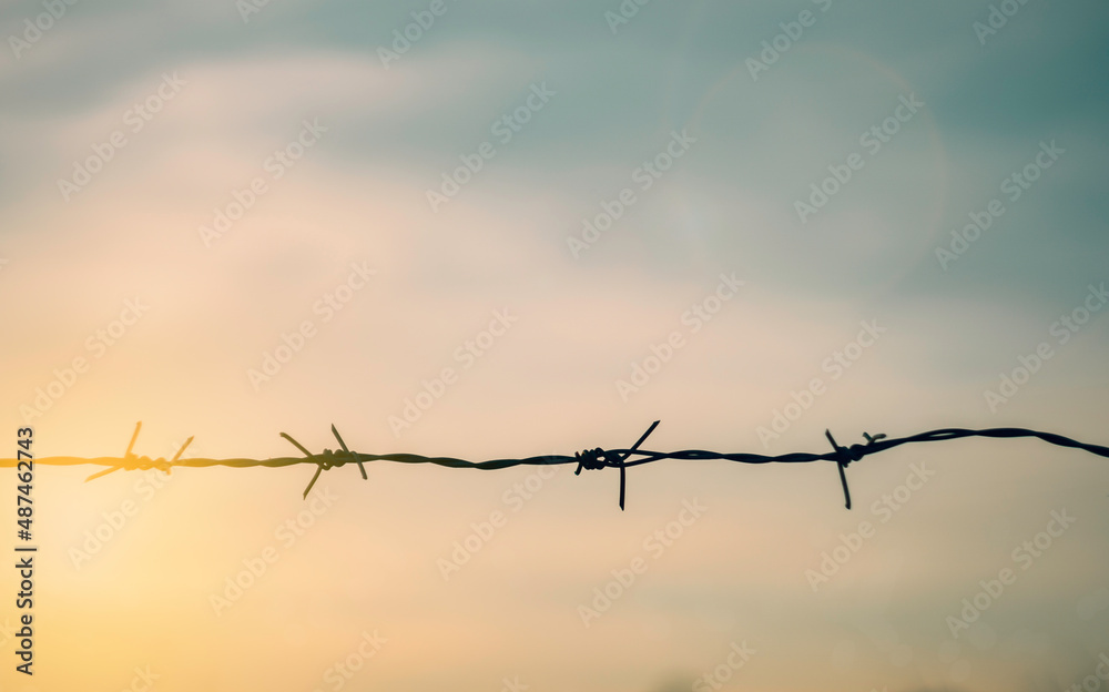 Barbed wire fence with sunset Twilight sky. Chain with spike for safety and security boundary concept for human rights slave, prison hostage hope to freedom. International liberty day. russia ukraine Barbed wire fence with sunset Twilight sky. Chain with spike for safety and security boundary concept for human rights slave, prison hostage hope to freedom. International liberty day. russia ukraine