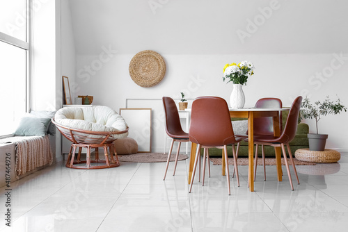 Vase with beautiful Chrysanthemum flowers on dining table, comfortable pouf and houseplants in room