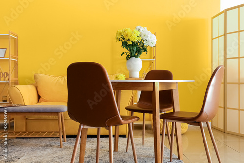 Vase with beautiful Chrysanthemum flowers on dining table in room