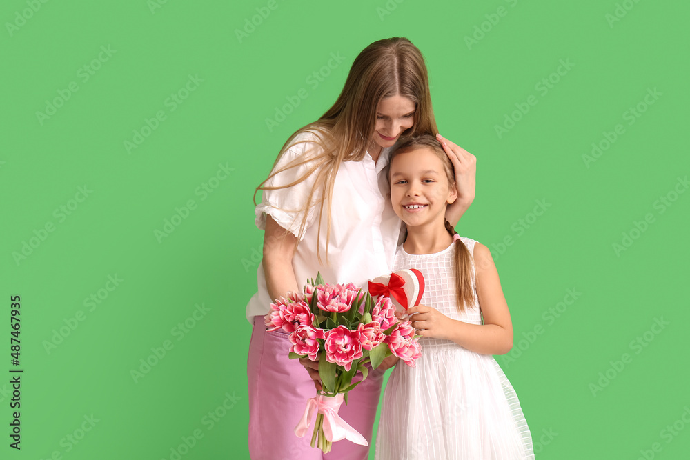 Little girl with her mother and gifts on green background Little girl with her mother and gifts on green background