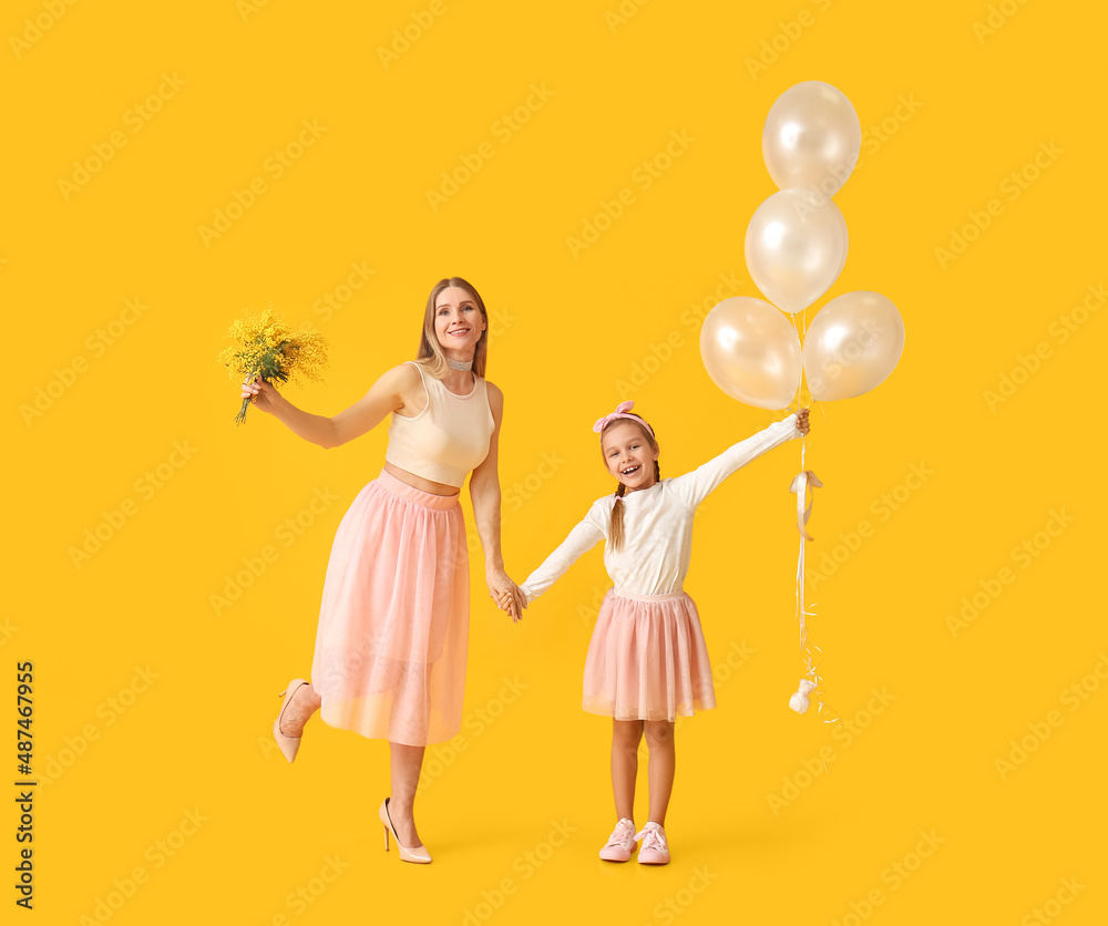 Little girl, her mother with flowers and balloons on yellow background Little girl, her mother with flowers and balloons on yellow background