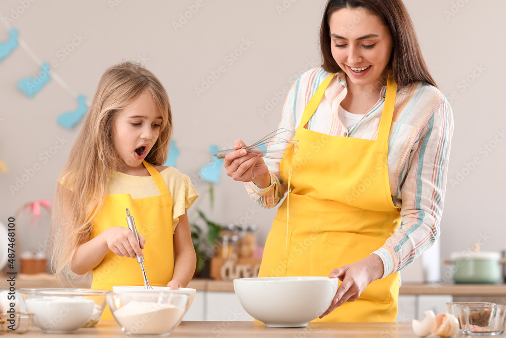 Little girl with her mother preparing dough for Easter cake in kitchen Little girl with her mother preparing dough for Easter cake in kitchen