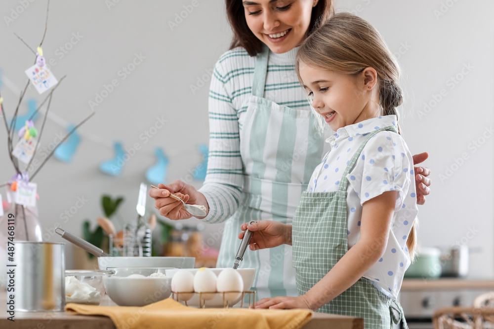 Little girl with her mother preparing dough for Easter cake in kitchen Little girl with her mother preparing dough for Easter cake in kitchen