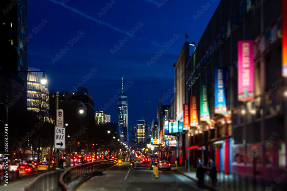 Naklejka premium New York City night street scene at Chelsea Pier with blurred lights of the buildings and cars