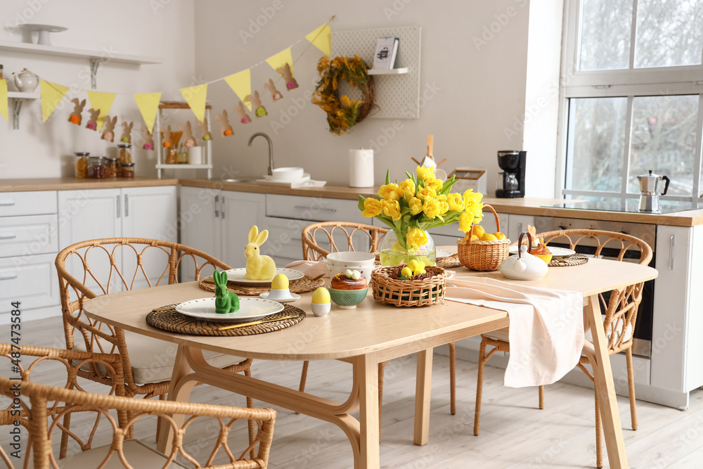 Festive table setting with yellow tulips and Easter rabbits in kitchen Festive table setting with yellow tulips and Easter rabbits in kitchen