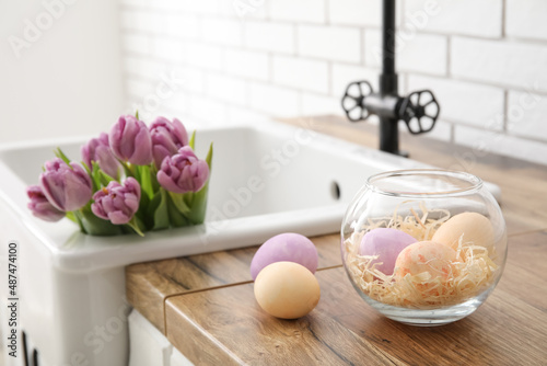 Easter eggs and sink with tulips on kitchen counter near white brick wall