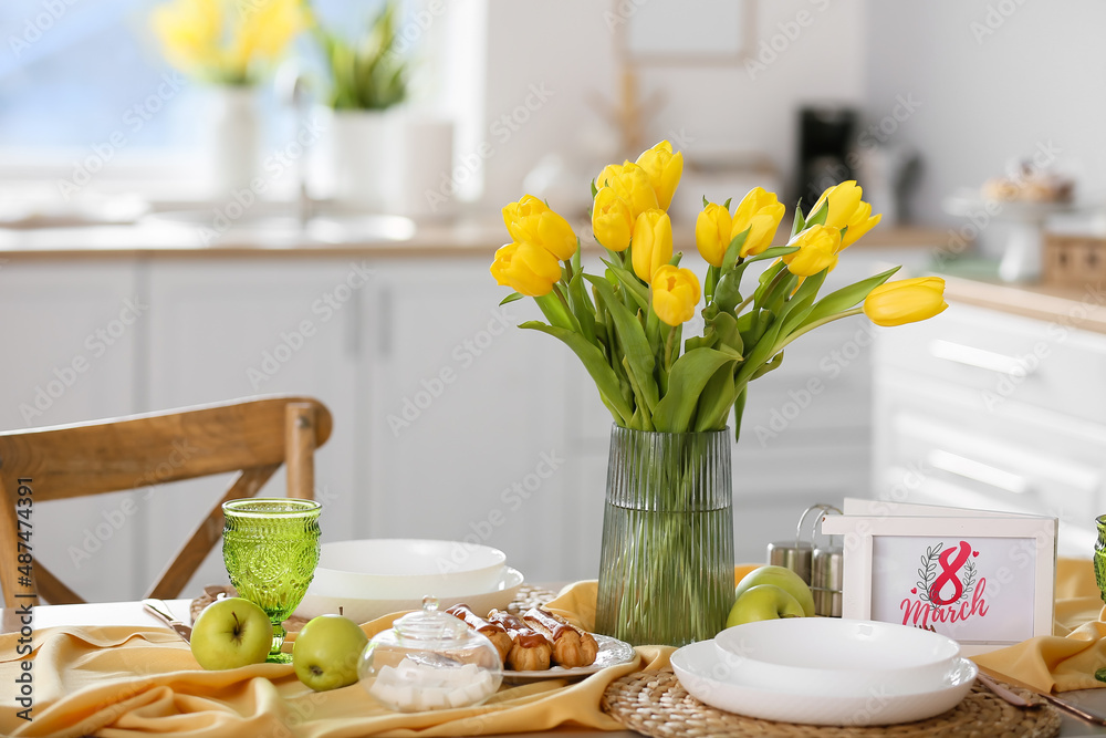 Vase with beautiful tulips and stylish setting on dining table. International Women's Day celebration