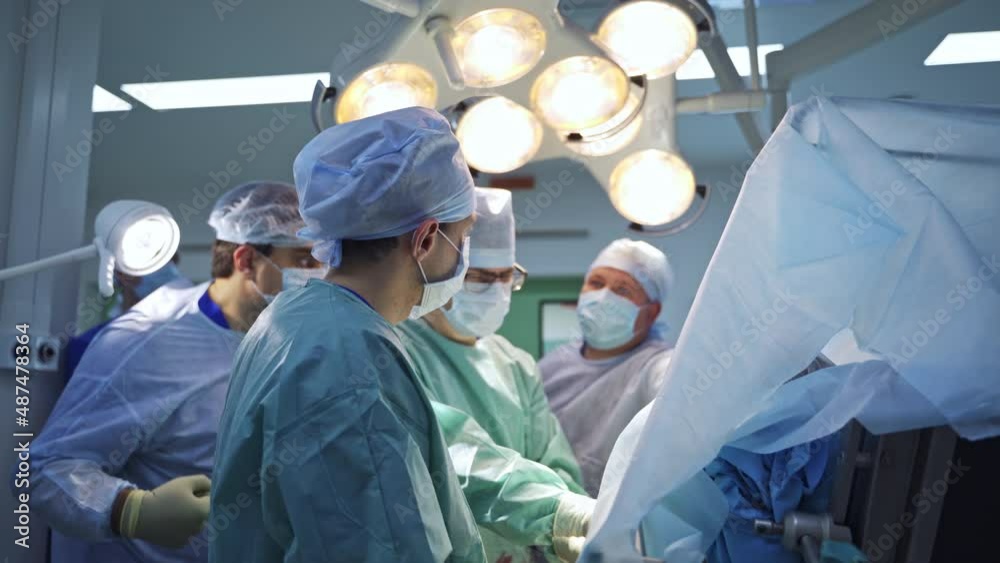 Spine trauma operation performed by a big group of surgeons. Doctors use metal tools and discuss the process together. Blurred backdrop. Spine trauma operation performed by a big group of surgeons. Doctors use metal tools and discuss the process together. Blurred backdrop.