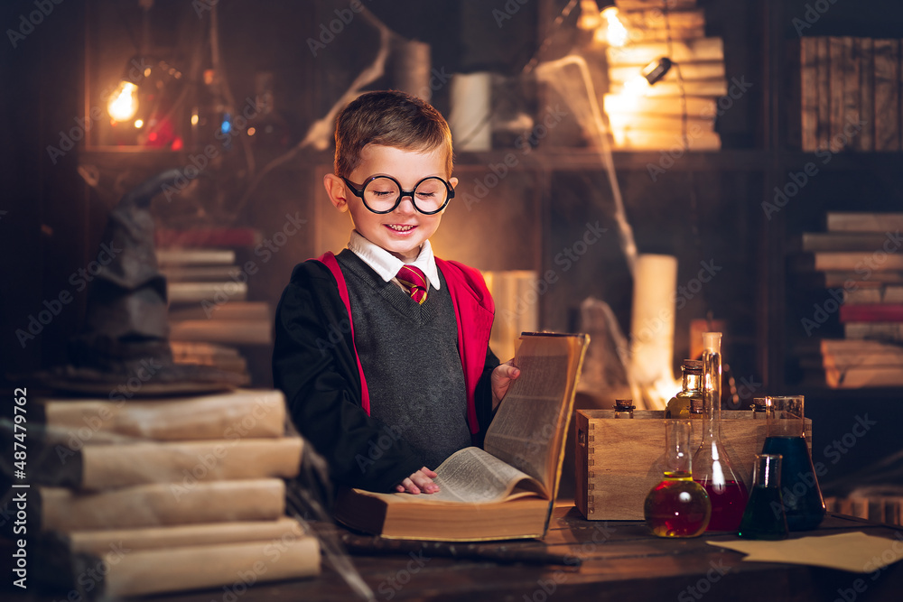 Fototapeta premium Small happy wizard reads magic book Cosplay. Halloween costume party. Decorate studio background 