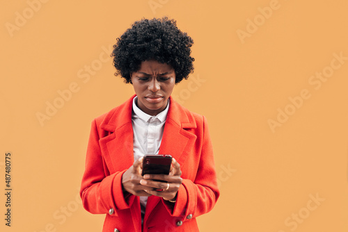 Young woman looking confused and worried while reading something on the mobile phone. Technology concept.