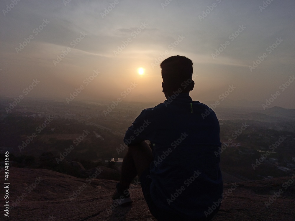 silhouette of a person in the sunset, person watching Sun set on top of mountain.