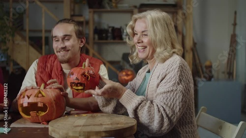 Elderly parents and their son are showing handmade halloween pumpkins on the video