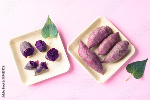 Purple sweet potatoes on natural plate with pink background, Top view photo