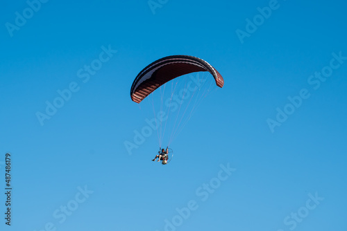 person flying in paragliding, sunny sky in the background