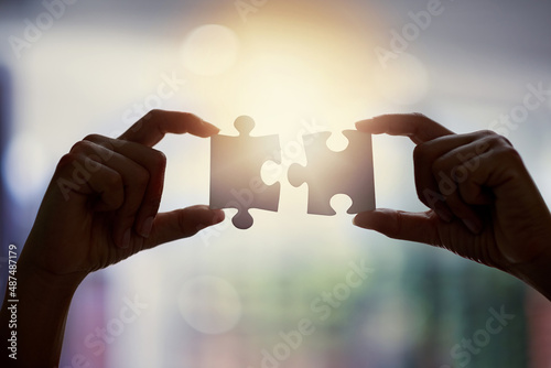 See the bigger picture. Closeup shot of an unidentifiable businesswoman holding two puzzle pieces together.