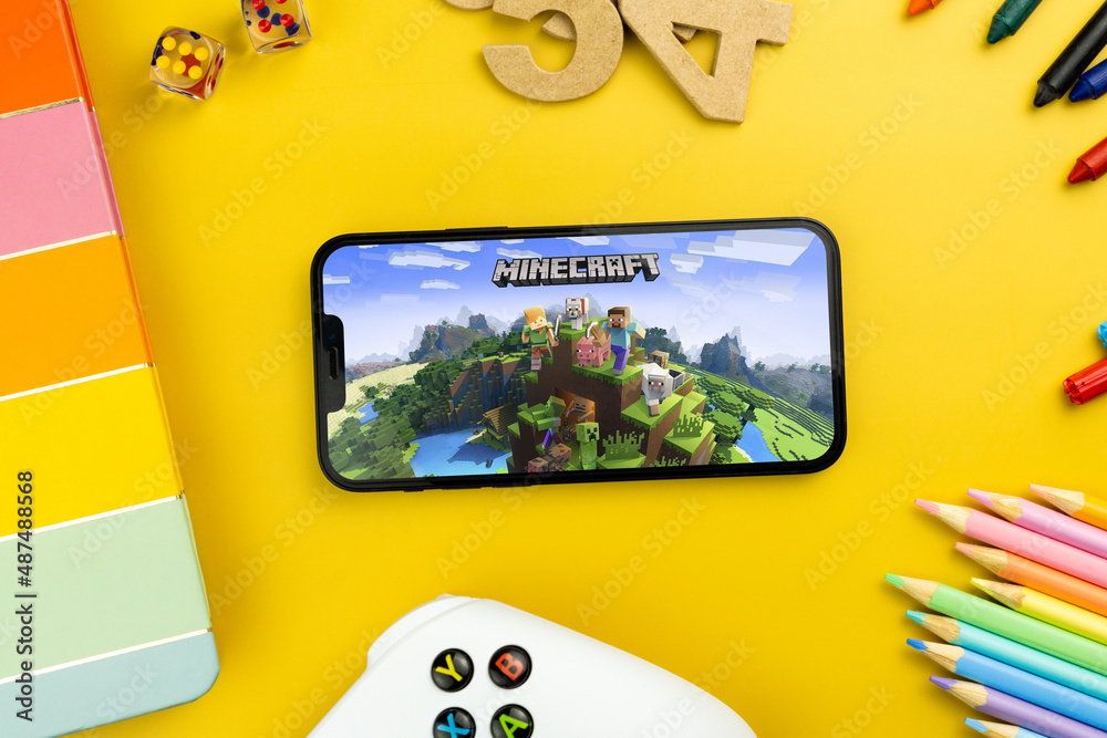 Naklejka premium Minecraft mobile game app on the smartphone screen. Yellow background with school supplies, children's accessories, video game controller. Rio de Janeiro, RJ, Brazil. February 2022