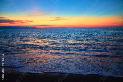 atardecer en el mar con un suave movimiento de olas en la arena reflejos del atardecer en el agua con un cielo azul y hermosos colores en el horizonte en las playas de puerto vallarta jalisco 