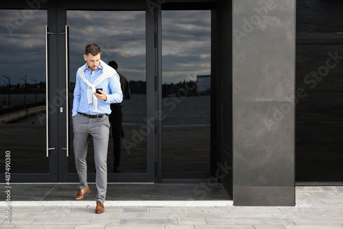 Handsome businessman using mobile phone near office building