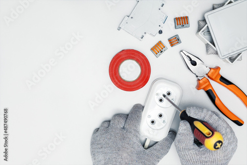 Electrician works with an electrical outlet on the desk. Top view with copy space. Different electrical equipment on white background.