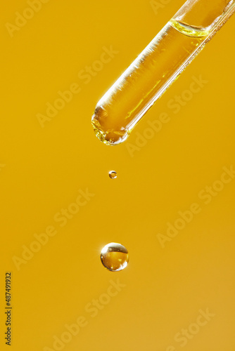 A drop of cosmetic aromatic oil drips from the pipette. Front view.