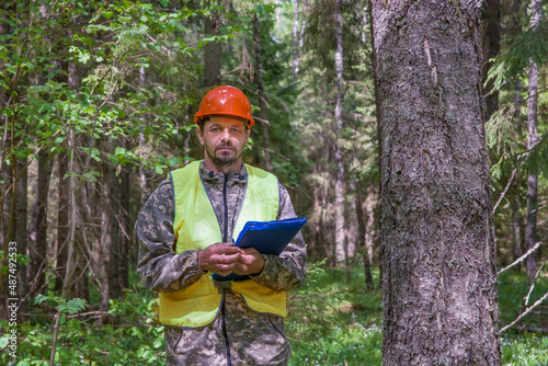 Forest engineer stands in the forest in working clothes.