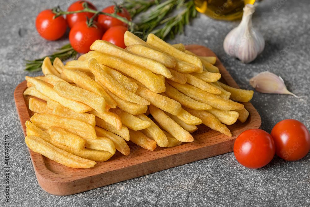 Wooden board with tasty french fries on grey background Wooden board with tasty french fries on grey background