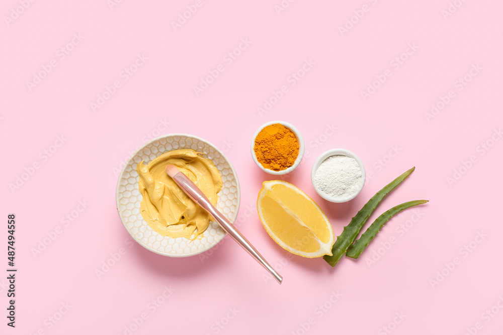 Bowl with turmeric mask, powder, lemon and aloe on pink background Bowl with turmeric mask, powder, lemon and aloe on pink background