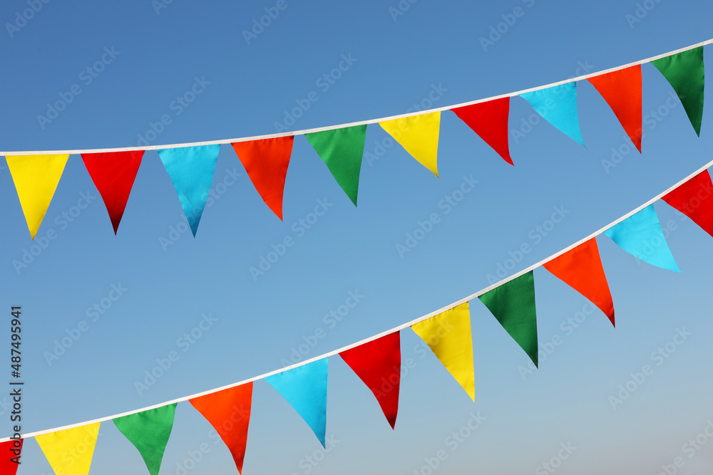Obraz premium Buntings with colorful triangular flags against blue sky