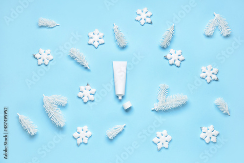 Opened tube with cream and winter decor on color background
