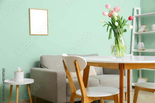 Vase with beautiful tulip flowers on dining table in room © Pixel-Shot