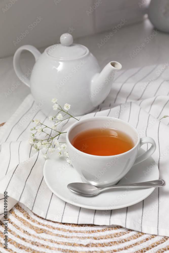 White teapot with saucer and cup of tea on countertop in kitchen White teapot with saucer and cup of tea on countertop in kitchen
