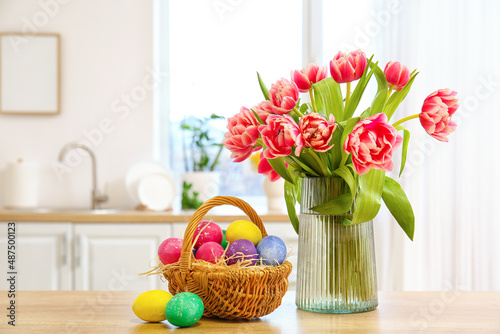 Photography Basket of Easter eggs and vase with tulips on kitchen counter in light room
