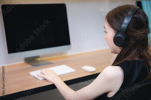 Female in headphone working or video call with computer desktop in modern office