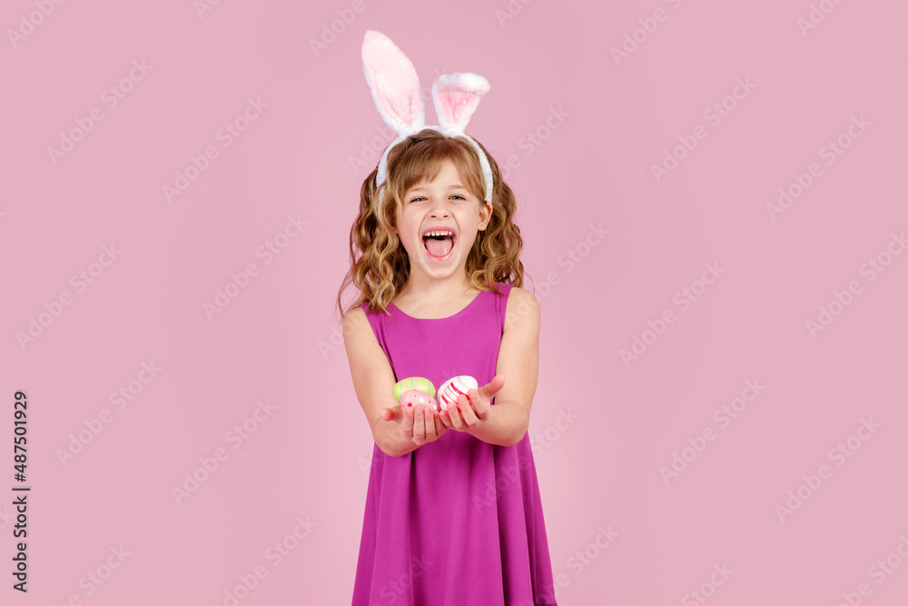 Smiling little girl with bunny hairband and easter eggs in hands. Vertical orientation