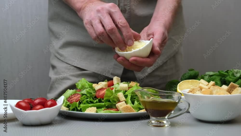 A male chef prepares a healthy and delicious vegetarian Caesar salad. The cook sprinkles the salad with parmesan cheese. Close-up. Slow motion. Step by step video instruction. Recipe. Step 4. A male chef prepares a healthy and delicious vegetarian Caesar salad. The cook sprinkles the salad with parmesan cheese. Close-up. Slow motion. Step by step video instruction. Recipe. Step 4.