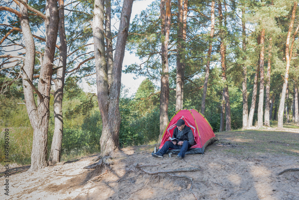 Fototapeta premium Man sitting in the forest near the tent.