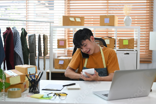 Small business owner wearing an apron talking on mobile phone for receive order from customer.