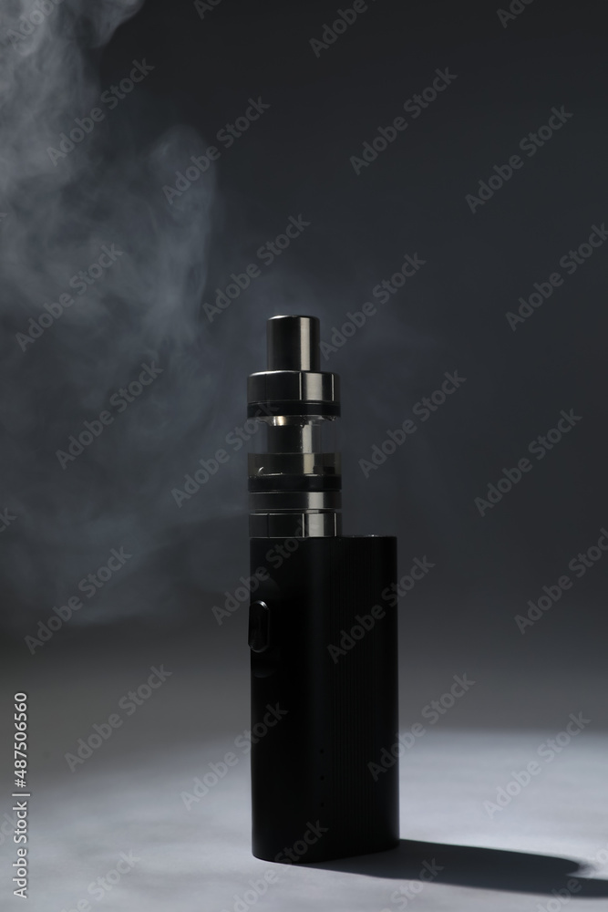 Fototapeta premium Electronic cigarette and smoke on dark grey background