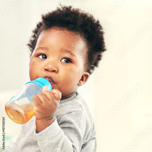 I love my sippy cup. Shot of a little baby boy drinking froma sippy cup at home. photo