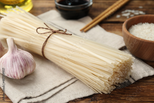 Uncooked rice noodles on wooden table, closeup